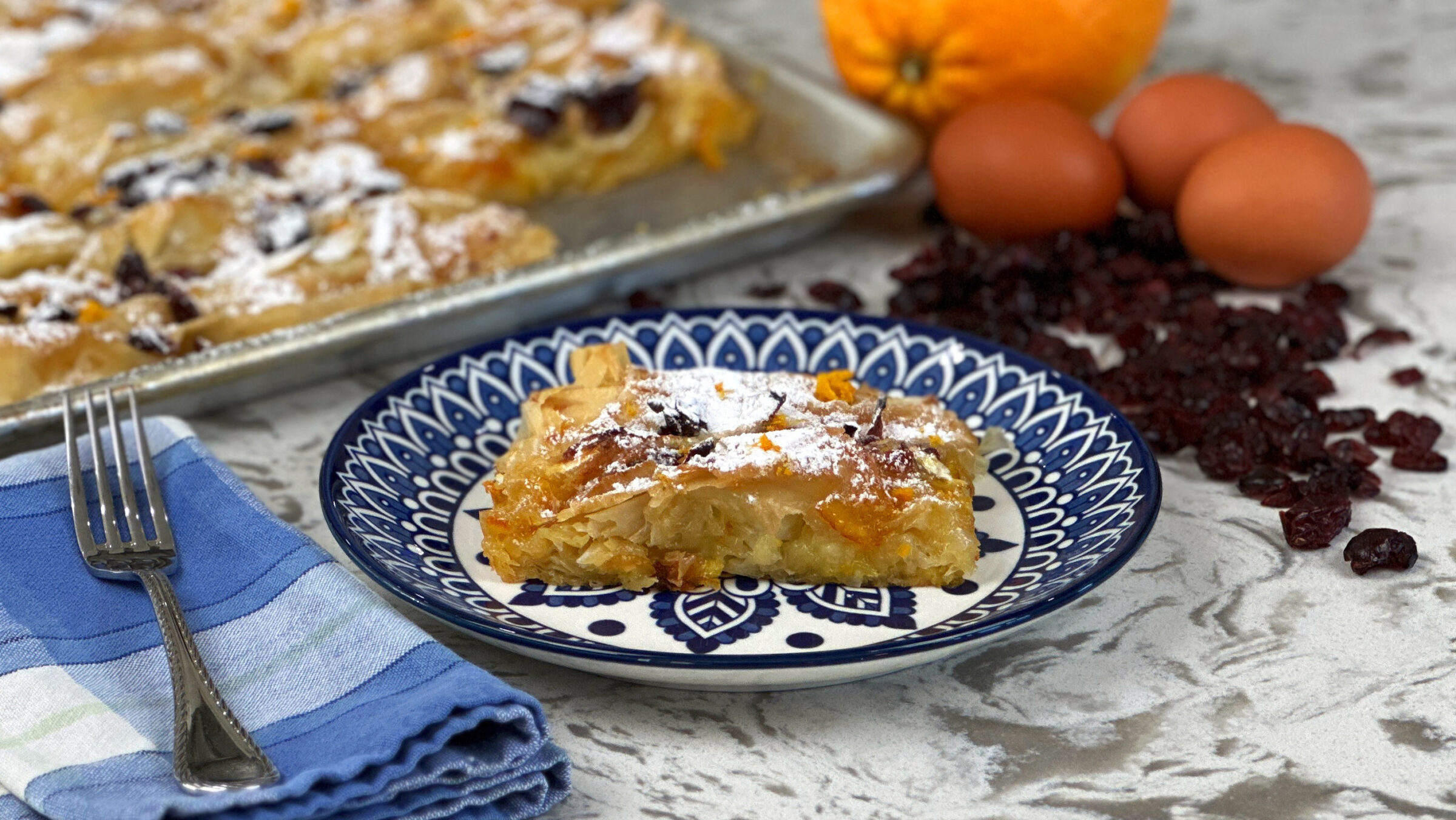 Phyllo pie on blue plate with fork orange eggs and dried cranberries