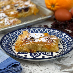 Phyllo pie on blue plate with fork orange eggs and dried cranberries