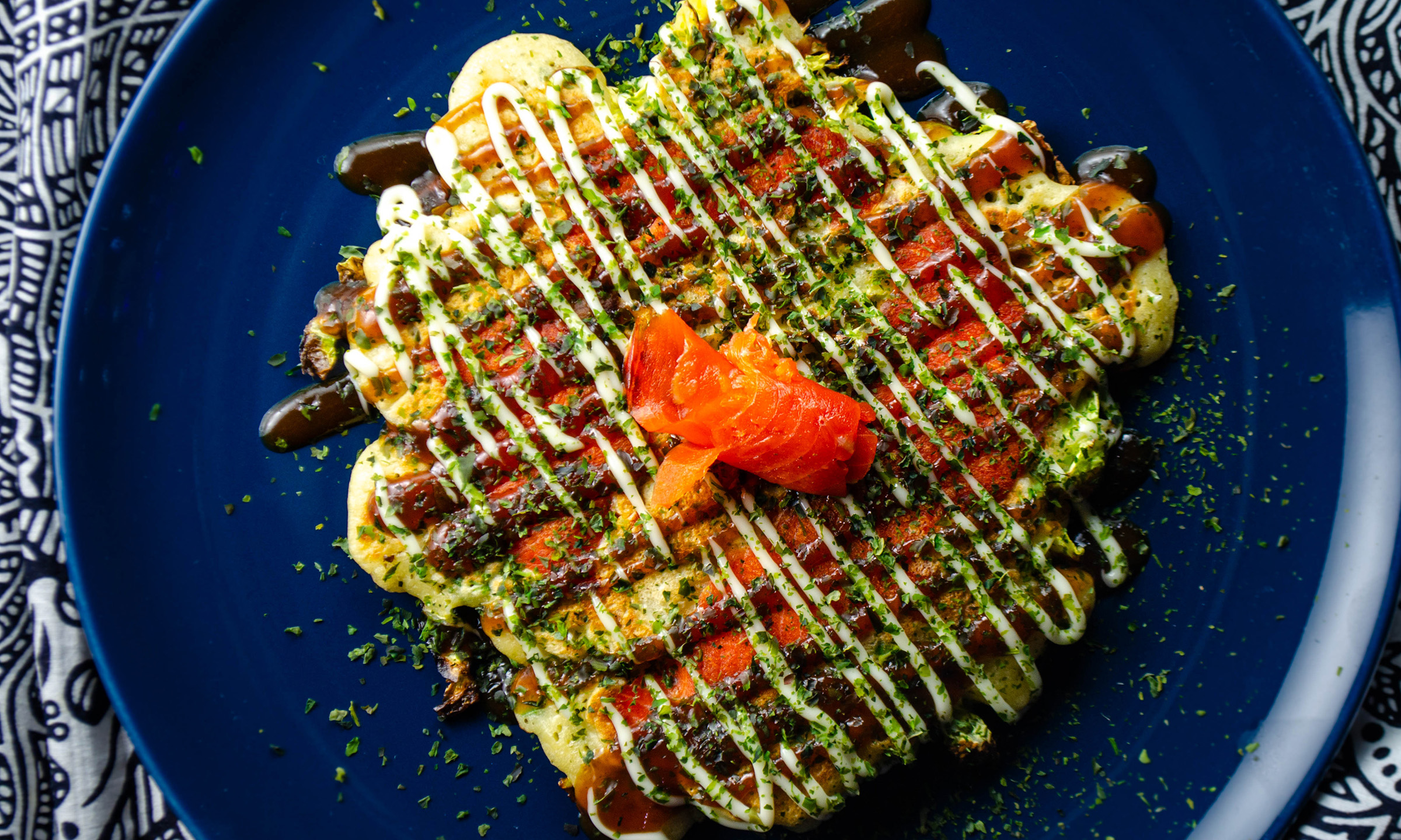 okonomiyaki Japanese pancake on a blue plate with smoked salmon